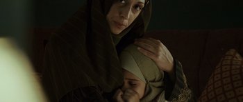 Movie still from “The Kingdom” (2007), directed by Peter Berg – A woman holding a child in her arms; Close Up shot, High angle