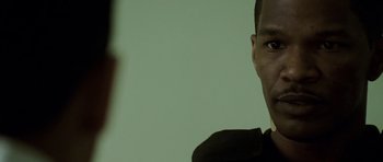 Movie still from “The Kingdom” (2007), directed by Peter Berg – A man's face in front of a green background; Close Up shot, Over the shoulder angle
