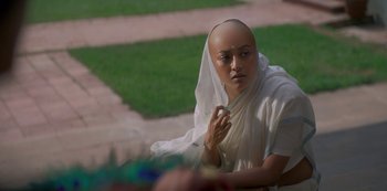 A person with a bald head sitting on the ground