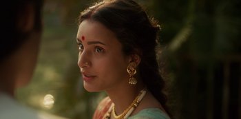 A beautiful woman with long brown hair wearing a necklace and earrings