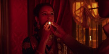 A woman lighting a candle in a dark room