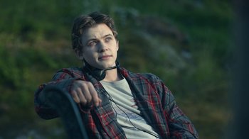 Movie still from “The Midnight Club” (2022), created by Mike Flanagan – A young man wearing a plaid shirt and headphones; Medium shot, High angle