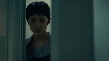 Movie still from “The Midnight Club” (2022), created by Mike Flanagan – A young man with short black hair is looking at the camera; Close Up shot, Over the shoulder angle