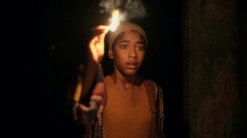 Movie still from “The Midnight Club” (2022), created by Mike Flanagan – A young man holding a lit candle in the dark; Close Up shot, High angle