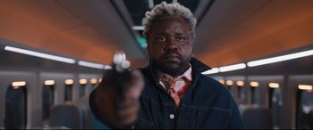 Movie still from “Bullet Train” (2022), directed by David Leitch – A man with a gun in his hand; Close Up shot, Low angle