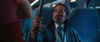 Movie still from “Bullet Train” (2022), directed by David Leitch – A man in a suit and tie holding a cane; Medium shot, Over the shoulder angle