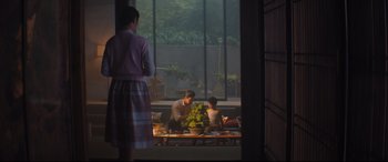Movie still from “Bullet Train” (2022), directed by David Leitch – A man and a woman sitting at a table with a potted plant in front of them; Wide shot, Over the shoulder angle