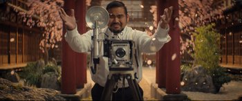 Movie still from “Bullet Train” (2022), directed by David Leitch – A man standing in front of an old style camera; Medium shot, Low angle