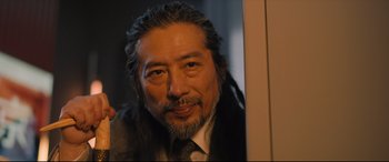 Movie still from “Bullet Train” (2022), directed by David Leitch – A person wearing a suit and tie; Close Up shot, Low angle