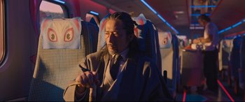 Movie still from “Bullet Train” (2022), directed by David Leitch – A man sitting on a seat on an airplane; Medium shot, Over the shoulder angle