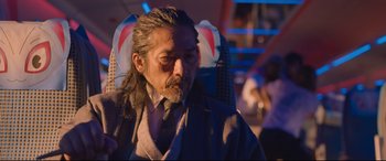 Movie still from “Bullet Train” (2022), directed by David Leitch – A man with long hair sitting in a chair; Close Up shot, Low angle