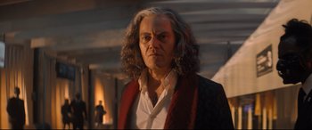 Movie still from “Bullet Train” (2022), directed by David Leitch – A man with long grey hair wearing a white shirt and a red jacket; Medium shot, Low angle