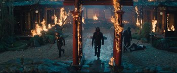 Movie still from “Bullet Train” (2022), directed by David Leitch – A group of people walking through a street with fire; Wide shot, High angle