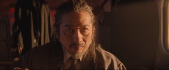 Movie still from “Bullet Train” (2022), directed by David Leitch – A person with long hair and a beard; Close Up shot, Over the shoulder angle