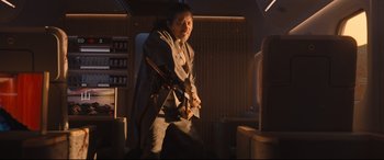 Movie still from “Bullet Train” (2022), directed by David Leitch – A man holding a pair of swords in a dark room; Medium shot, Over the shoulder angle