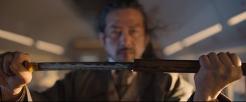 Movie still from “Bullet Train” (2022), directed by David Leitch – A man in a suit and tie holding a sword; Close Up shot, Low angle
