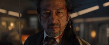 Movie still from “Bullet Train” (2022), directed by David Leitch – A person wearing a suit with blood on his face; Close Up shot, Low angle