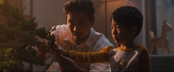 Movie still from “Bullet Train” (2022), directed by David Leitch – A man and a child looking at a plant; Medium shot, Over the shoulder angle