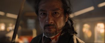 Movie still from “Bullet Train” (2022), directed by David Leitch – A person wearing a suit and tie; Close Up shot, Low angle