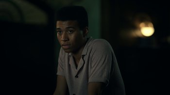 Movie still from “The Midnight Club” (2022), created by Mike Flanagan – A man sitting in a dark room looking at the camera; Close Up shot, Over the shoulder angle