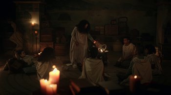 Movie still from “The Midnight Club” (2022), created by Mike Flanagan – A group of people sitting in a room with candles; Wide shot, High angle