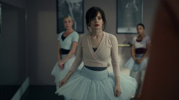 Movie still from “The Midnight Club” (2022), created by Mike Flanagan – A woman in a white skirt is standing in front of two other women; Medium shot, Over the shoulder angle