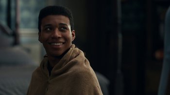 Movie still from “The Midnight Club” (2022), created by Mike Flanagan – A young man smiles while wrapped in a blanket; Close Up shot, Over the shoulder angle