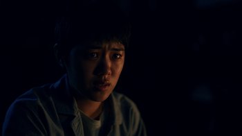 Movie still from “The Midnight Club” (2022), created by Mike Flanagan – A young man in a white shirt is looking at the camera; Close Up shot, Over the shoulder angle