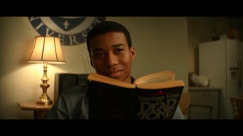 Movie still from “The Midnight Club” (2022), created by Mike Flanagan – A young man is holding an open book in his hands; Close Up shot, Over the shoulder angle