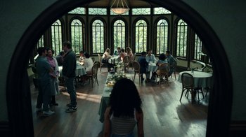 Movie still from “The Midnight Club” (2022), created by Mike Flanagan – A group of people sitting at a table in front of a window; Wide shot, High angle