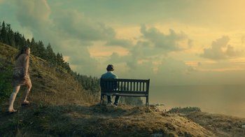 Movie still from “The Midnight Club” (2022), created by Mike Flanagan – A man sitting on a bench on top of a hill; Extreme Wide shot, High angle