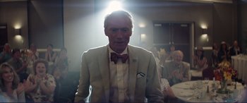 Movie still from “The Mule” (2018), directed by Clint Eastwood – A man wearing a suit and bow tie in front of a group of onlookers; Close Up shot, Low angle