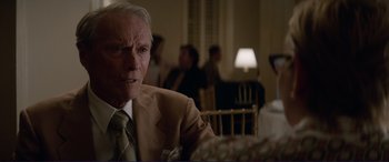 Movie still from “The Mule” (2018), directed by Clint Eastwood – An older man sitting at a table in front of a group of people; Close Up shot, Over the shoulder angle