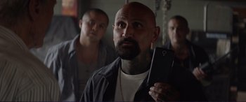 Movie still from “The Mule” (2018), directed by Clint Eastwood – A man with a beard holding up a cell phone; Close Up shot, Over the shoulder angle