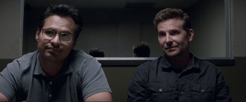 Movie still from “The Mule” (2018), directed by Clint Eastwood – Two men sitting next to each other in front of a wall; Medium shot, Over the shoulder angle