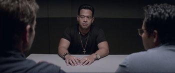 Movie still from “The Mule” (2018), directed by Clint Eastwood – A man sitting at a table in front of a wall; Medium shot, Over the shoulder angle