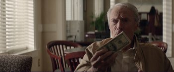 Movie still from “The Mule” (2018), directed by Clint Eastwood – An older man holding a dollar bill in his hands; Close Up shot, Low angle