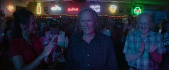 Movie still from “The Mule” (2018), directed by Clint Eastwood – A group of people standing in front of a neon sign; Medium shot, Over the shoulder angle