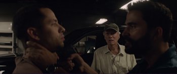 Movie still from “The Mule” (2018), directed by Clint Eastwood – An older man talking on a cell phone in front of another man; Close Up shot, Over the shoulder angle