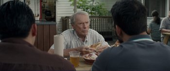 Movie still from “The Mule” (2018), directed by Clint Eastwood – An older man sitting at a table with a bowl of pizza; Medium shot, Over the shoulder angle