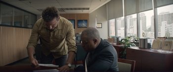 Movie still from “The Mule” (2018), directed by Clint Eastwood – Two men in an office looking at a book; Medium shot, Over the shoulder angle