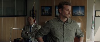 Movie still from “The Mule” (2018), directed by Clint Eastwood – Two men are sitting in front of an american flag; Medium shot, Over the shoulder angle