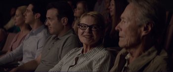 Movie still from “The Mule” (2018), directed by Clint Eastwood – A woman wearing glasses sitting in front of other people; Close Up shot, Over the shoulder angle