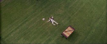 Movie still from “The Mule” (2018), directed by Clint Eastwood – A man laying in the grass holding a frisbee; Extreme Wide shot, Overhead angle