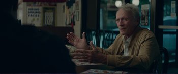 Movie still from “The Mule” (2018), directed by Clint Eastwood – An older man sitting at a table in front of a laptop; Medium shot, Over the shoulder angle