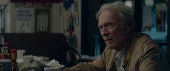 Movie still from “The Mule” (2018), directed by Clint Eastwood – An older man sitting at a table in a room; Close Up shot, Over the shoulder angle