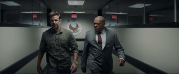 Movie still from “The Mule” (2018), directed by Clint Eastwood – Two men in suits are walking in a room; Medium shot, Over the shoulder angle