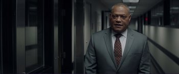 Movie still from “The Mule” (2018), directed by Clint Eastwood – A man wearing a suit and tie standing in a hallway; Medium shot, Low angle