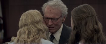 Movie still from “The Mule” (2018), directed by Clint Eastwood – An older man in a suit and tie with two young women; Close Up shot, Over the shoulder angle