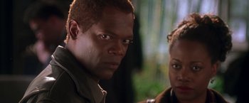 Movie still from “The Negotiator” (1998), directed by F. Gary Gray – A man and a woman standing next to each other in front of trees; Close Up shot, Over the shoulder angle